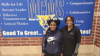  student and adult posing in front of sign
